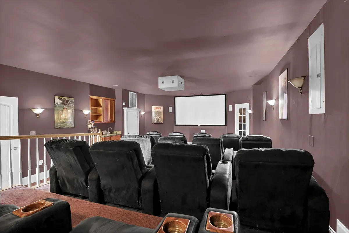 The image features a large projection screen flanked by several rows of comfortable, reclined seating, all set in a dimly lit, inviting space designed for an immersive movie-watching experience.