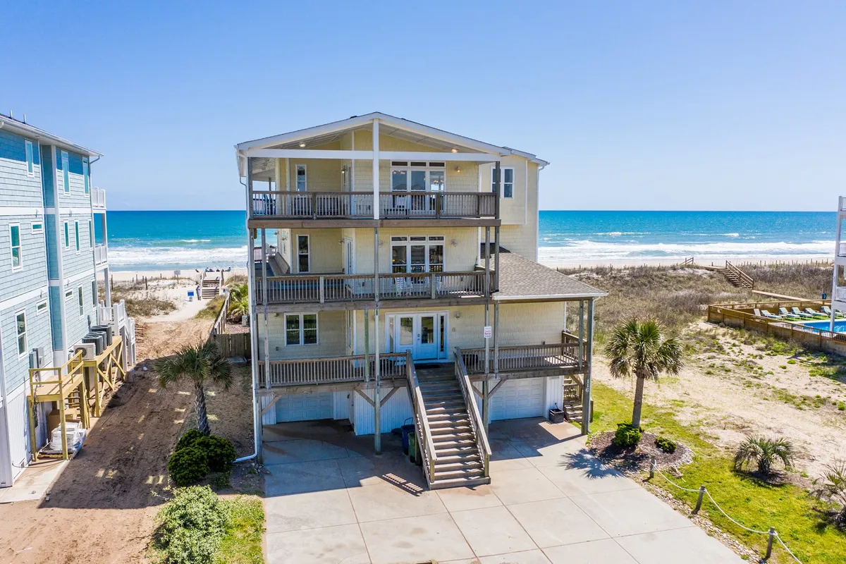 This image showcases a beachfront view with spacious balconies and palm trees, highlighting direct access to the sand and plenty of outdoor space for families and pets to enjoy. The open beach and decks evoke relaxation and are ideal for long walks with dogs or lounging together outside.