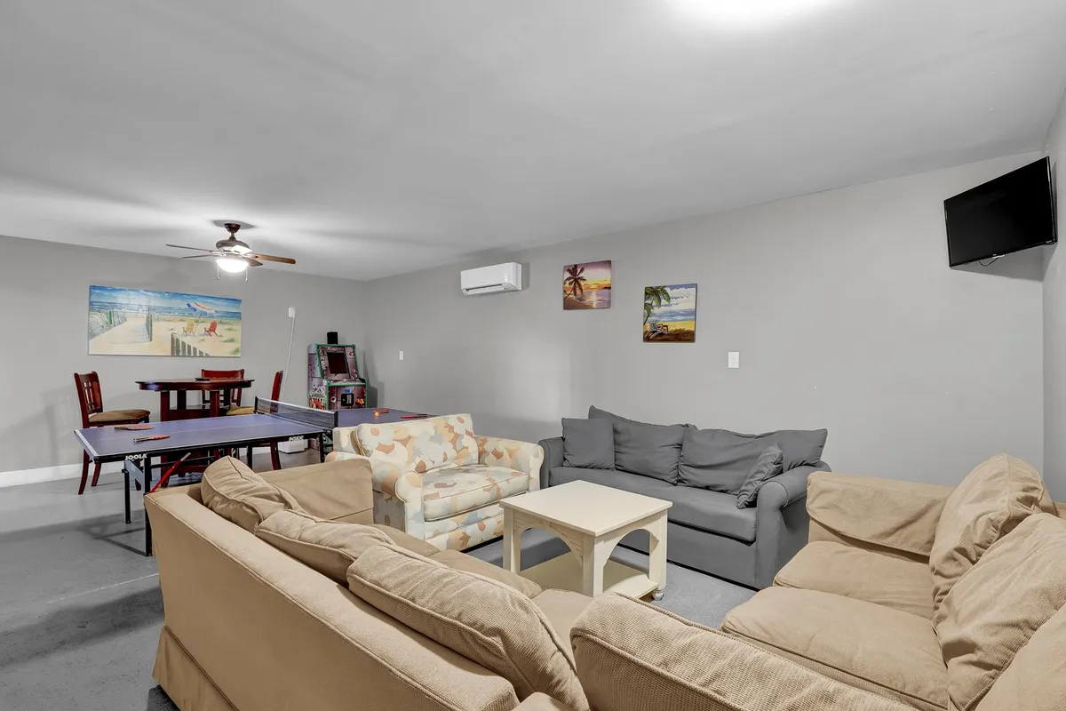 A bright, welcoming game room with a ping pong table and a cozy sofa seating area is shown here. The walls are decorated with cheerful artwork, and the space encourages both spirited competition and relaxed socializing.